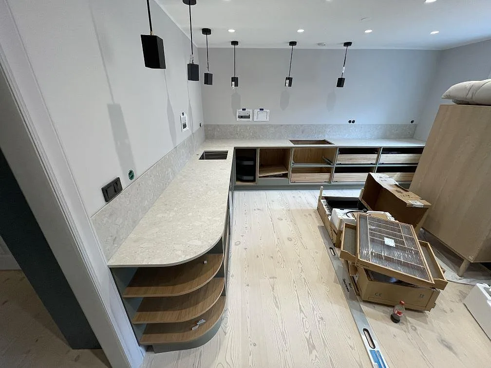 Köksbänkskiva i matt Dekton Ava med uppvikt stänkskydd, diskho och hällöppning i ett kök under montering i Stockholm.