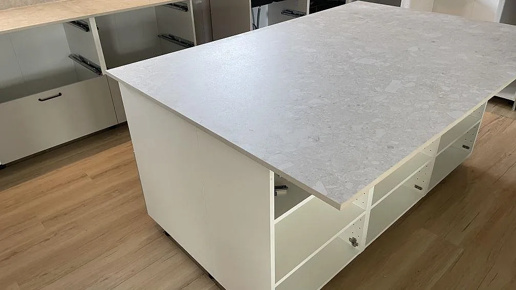 Närbild på köksö med bänkskiva i matt Dekton Ava keramik och ljusa köksstommar under montering i Tollarp.