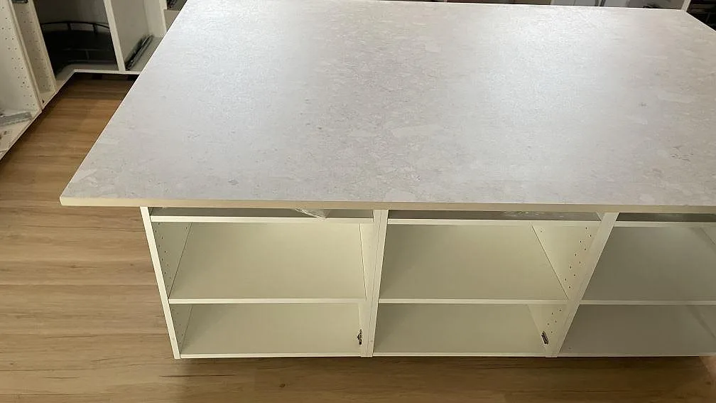 Framsida av köksö med bänkskiva i matt Dekton Ava keramik och öppna köksstommar i Tollarp.
