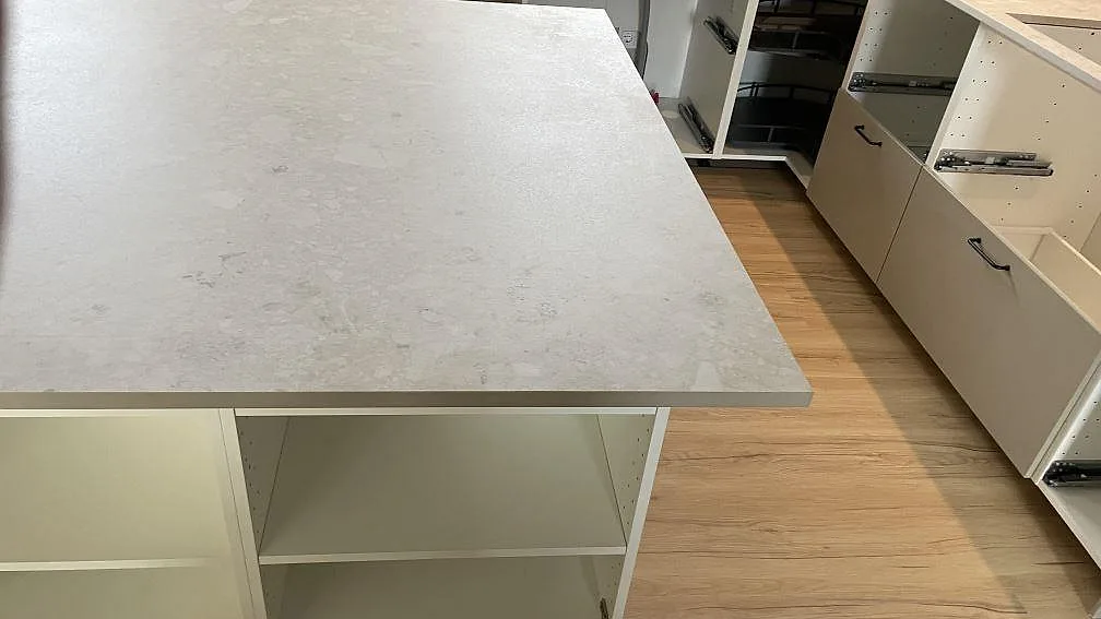 Detalj av köksö i matt Dekton Ava keramik med köksrad och lådor under montering i Tollarp.