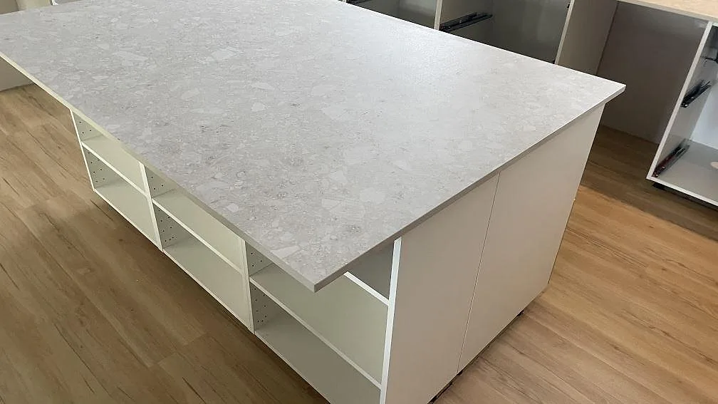 Köksö i matt Dekton Ava keramik sedd från hörnet med ljusa stommar och trämönstrat golv i Tollarp.