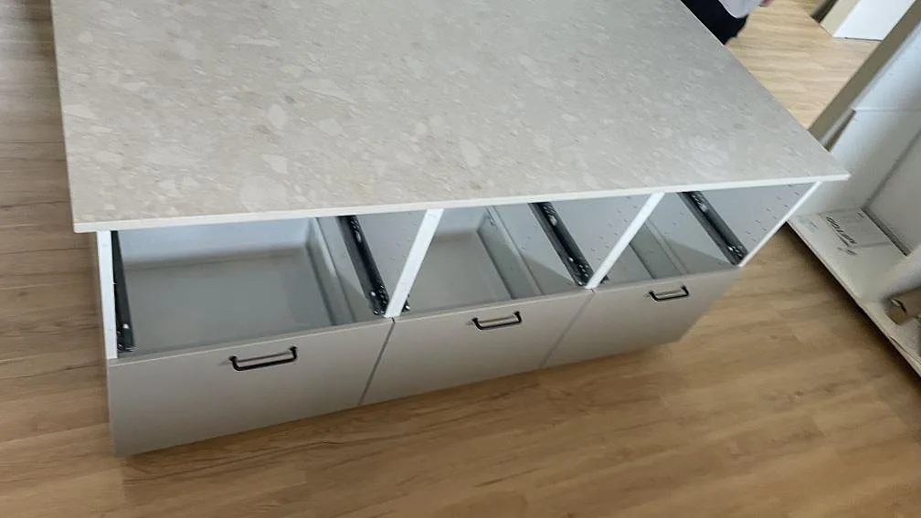 Köksö med utdragslådor under en matt Dekton Ava bänkskiva i keramik under montering i Tollarp.
