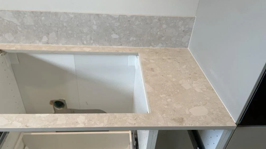 Hörn på bänkskiva i matt Dekton Ava keramik med utsågning och uppvikt stänkkant i kök i Tollarp.