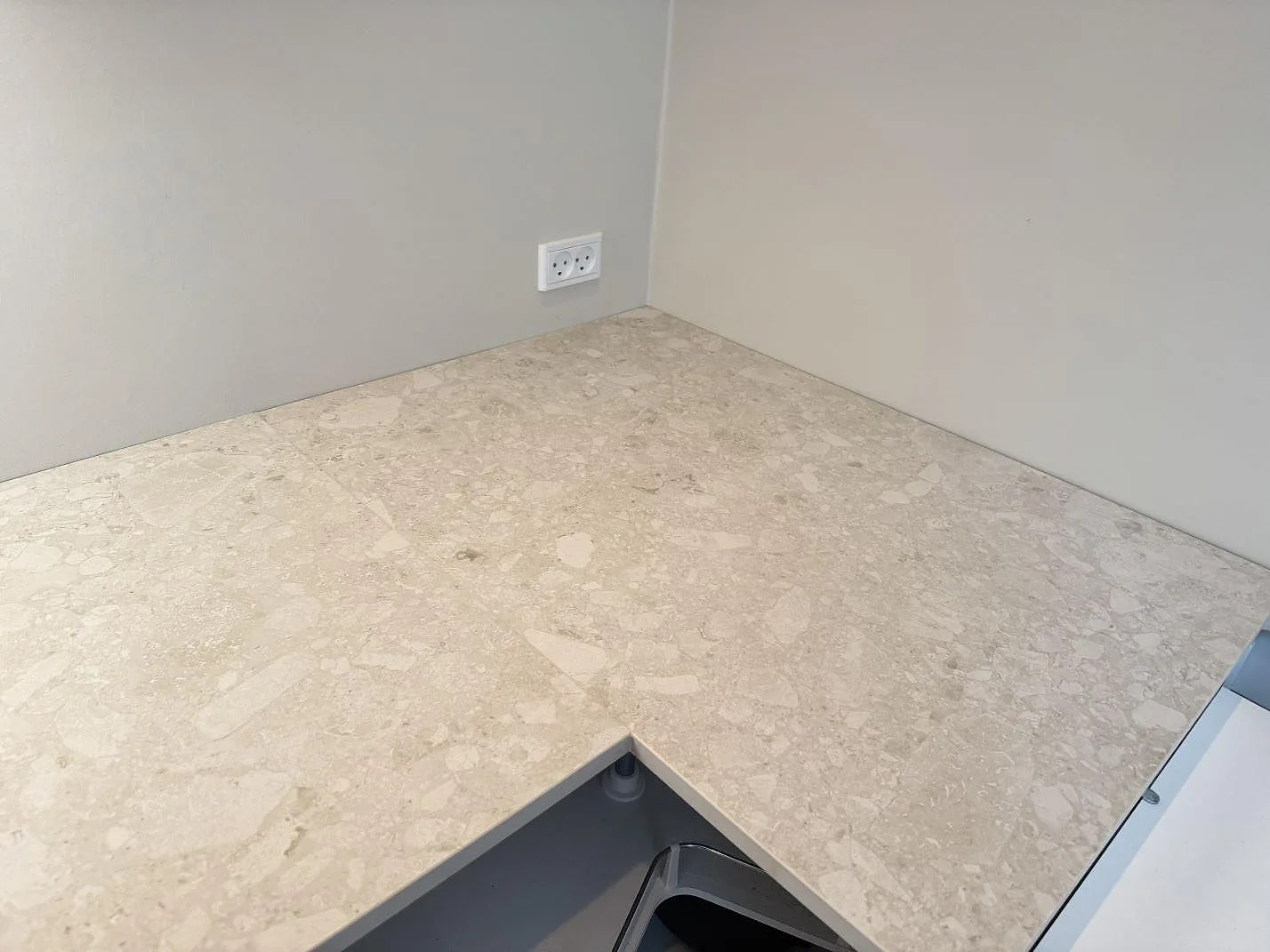 Närbild på hörnet i en köksbänkskiva av matt Dekton Ava, ljus keramik, med öppna stommar i Værløse.