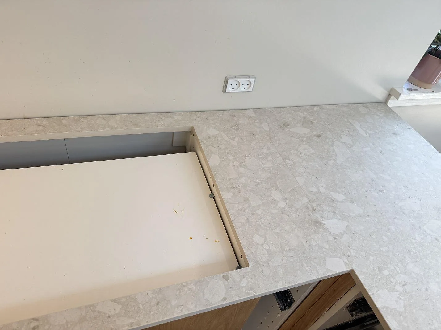Köksbänkskiva i matt Dekton Ava med bearbetad öppning, vägguttag och trästommar i ett kök i Værløse.