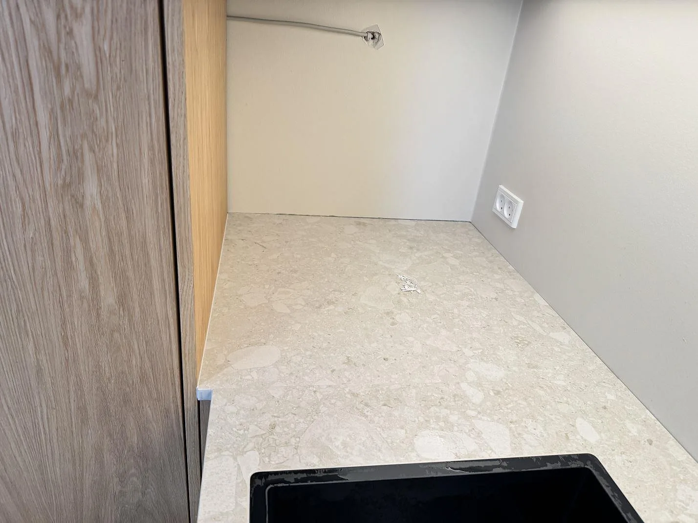 Matt Dekton Ava köksbänkskiva i ljus keramik vid vägg och träinredning, med mörk diskho i ett kök i Værløse.