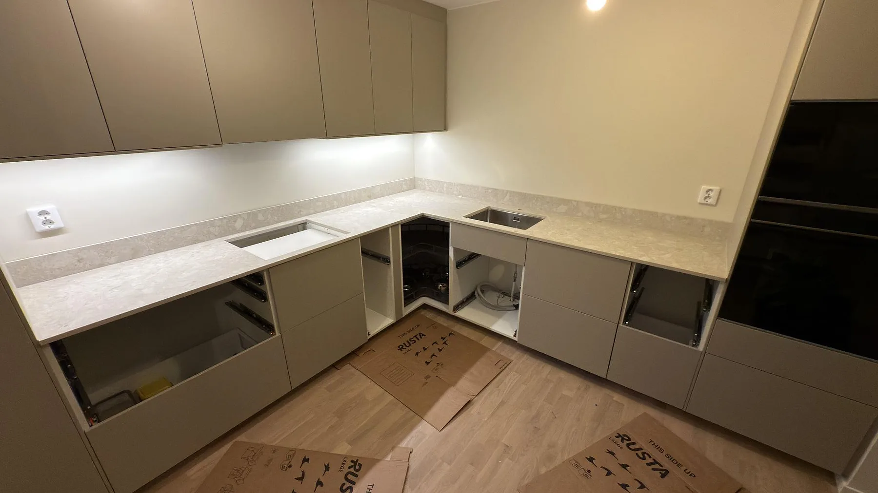 Matt köksbänkskiva i Dekton Ava med låg stänkkant, diskho och hällöppning i ett kök i Västerås.
