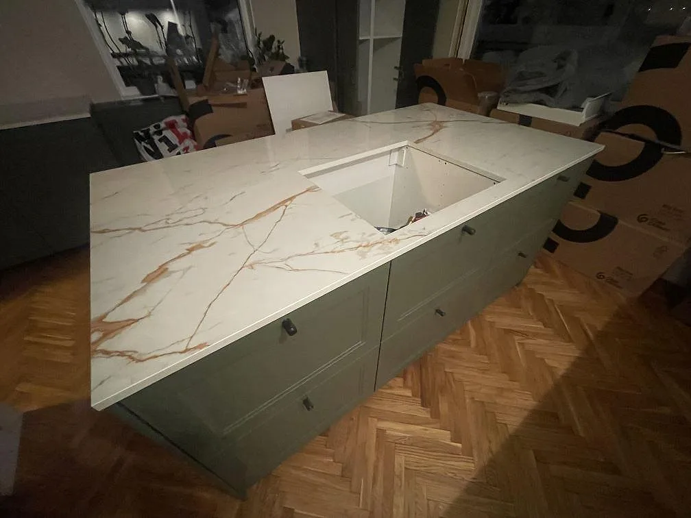 Köksö i Dekton Awake med markant gyllene ådring och urtag för häll, polerad yta, i ett kök i Enskede under montering.