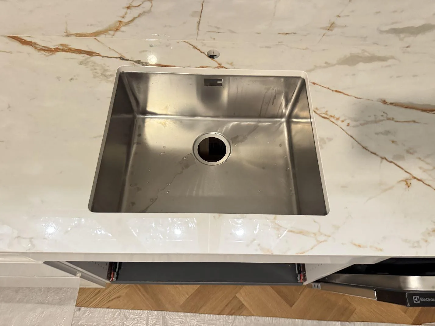 Närbild ovanifrån på underlimmad rostfri diskho i polerad Dekton Awake köksbänkskiva i Göteborg.