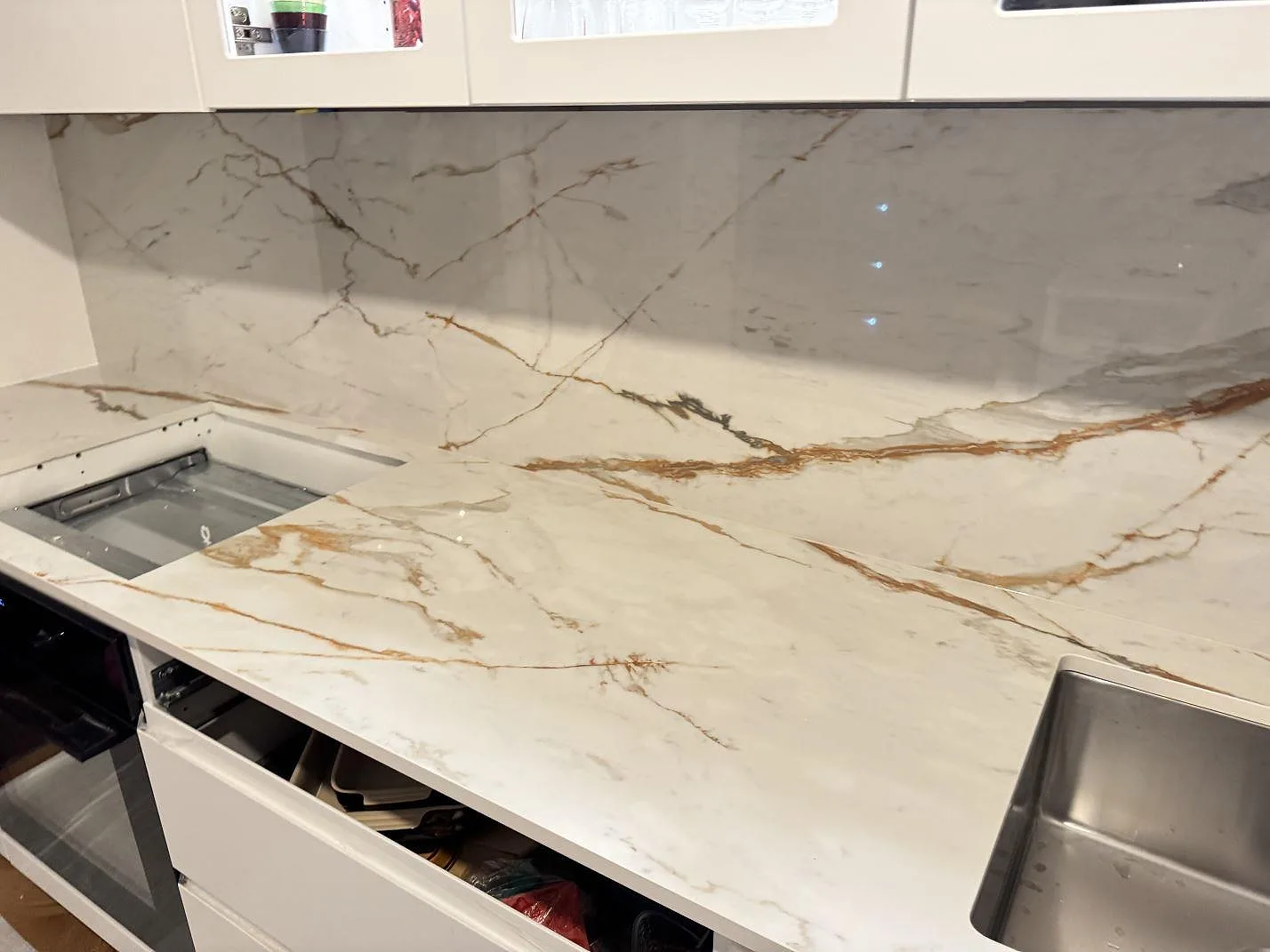 Köksbänk i Dekton Awake med urtag för infälld häll och en andra underlimmad rostfri diskho, polerad vit keramik, Göteborg.
