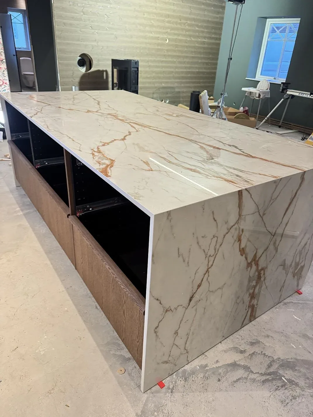 Köksö i polerad Dekton Awake med fallande gavel och tydlig rosttonad ådring, monterad på öppna köksstommar i Osby.