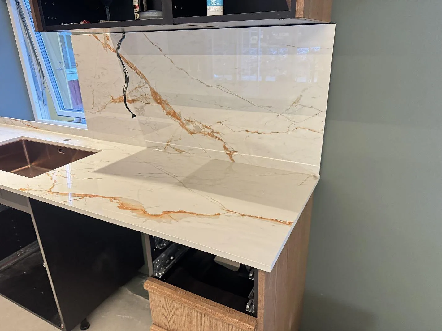Detalj av polerad Dekton Awake som bänkskiva och stänkskydd med synlig diskho i ett kök i Osby.
