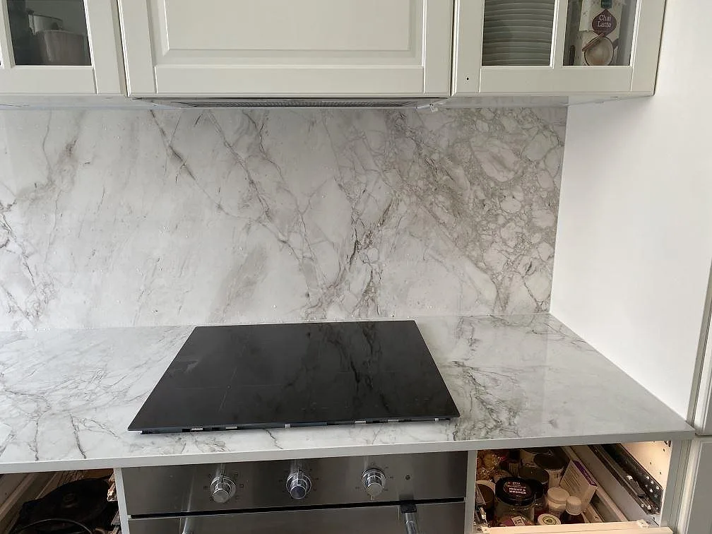 Infälld induktionshäll i polerad Dekton Bergen bänkskiva med heltäckande stänkvägg i samma sten i ett kök i Frederiksberg.