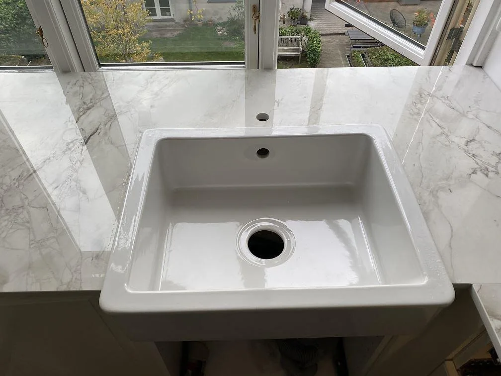 Vit keramikho monterad under bänkskivan i Dekton Bergen i ett kök i Frederiksberg, sedd ovanifrån.