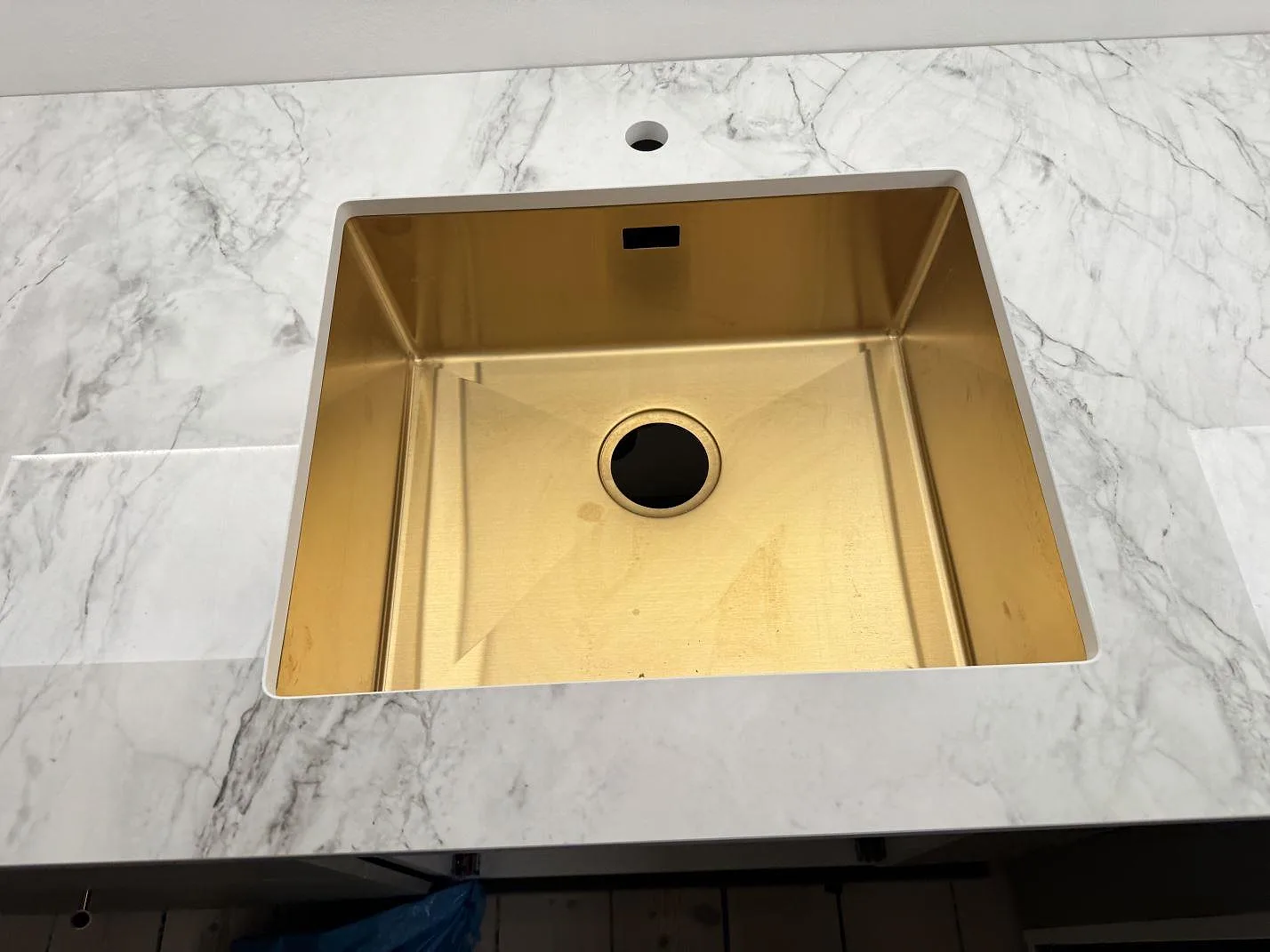 Närbild på diskho i polerad Dekton Bergen bänkskiva, ljus keramik med grå ådring i ett kök i Frederiksberg.