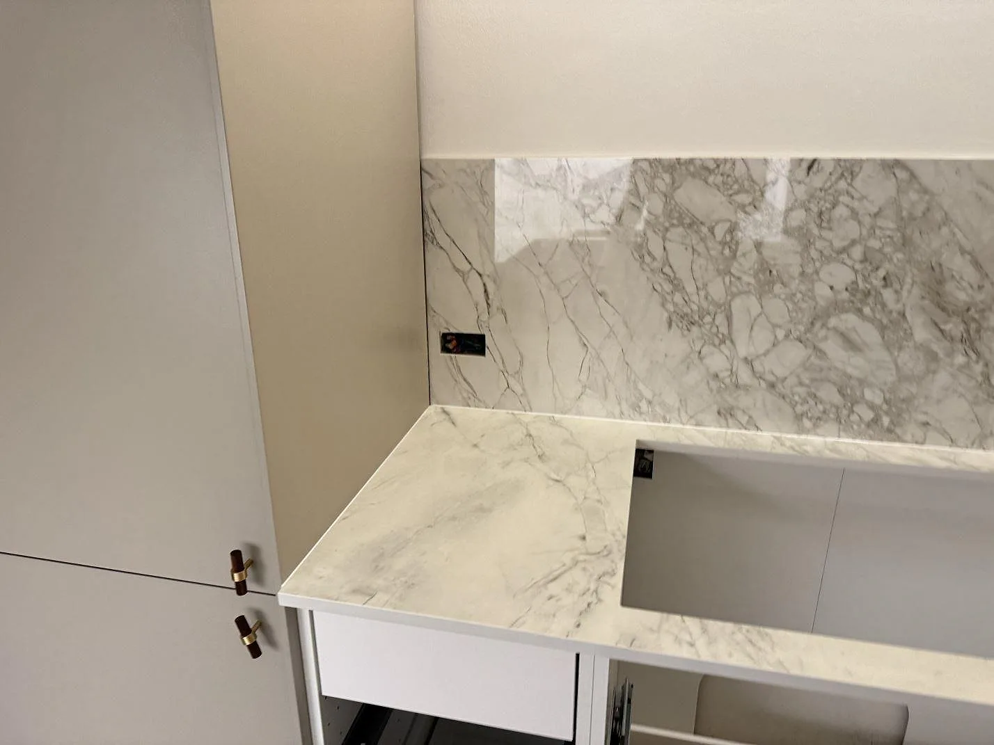 Polerad Dekton Bergen bänkskiva och väggbeklädnad med grå ådring i ett kök under montering i Frederiksberg.