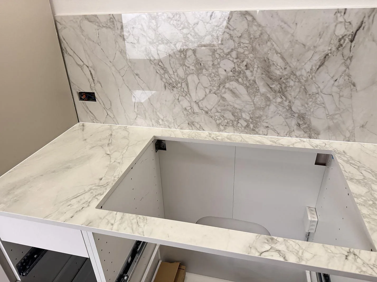 Bänkskiva och stänkskydd i polerad Dekton Bergen keramik med stort öppet urtag under montering i Frederiksberg.
