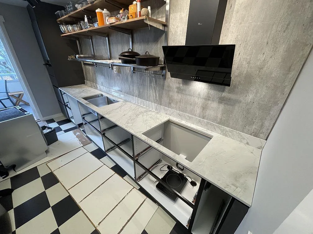 Polerad köksbänkskiva i Dekton Bergen med diskho och utskärning för häll längs en köksvägg i Gustavsberg.