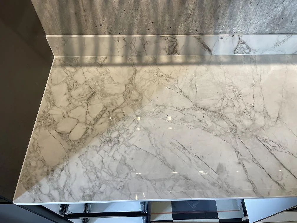 Närbild på polerad Dekton Bergen i keramik med grå ådring och stänkkant över köksbänken i Gustavsberg.
