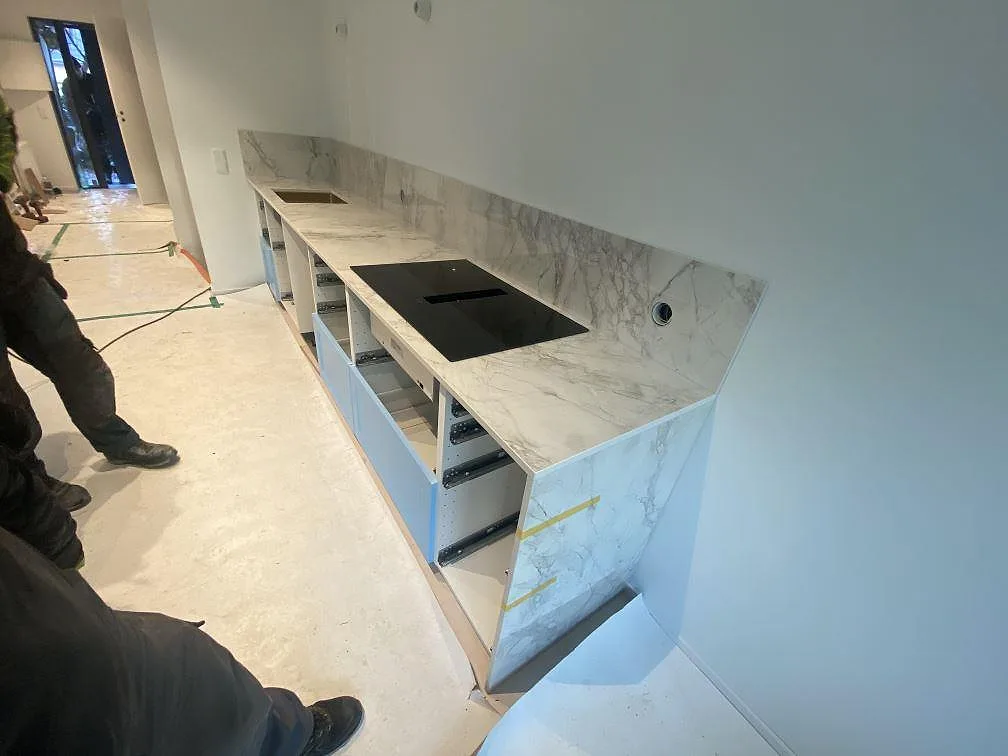 Polerad köksbänkskiva i Dekton Bergen, 20 mm keramik, med svart induktionshäll och uppvikt stänkskydd i Hjärup.