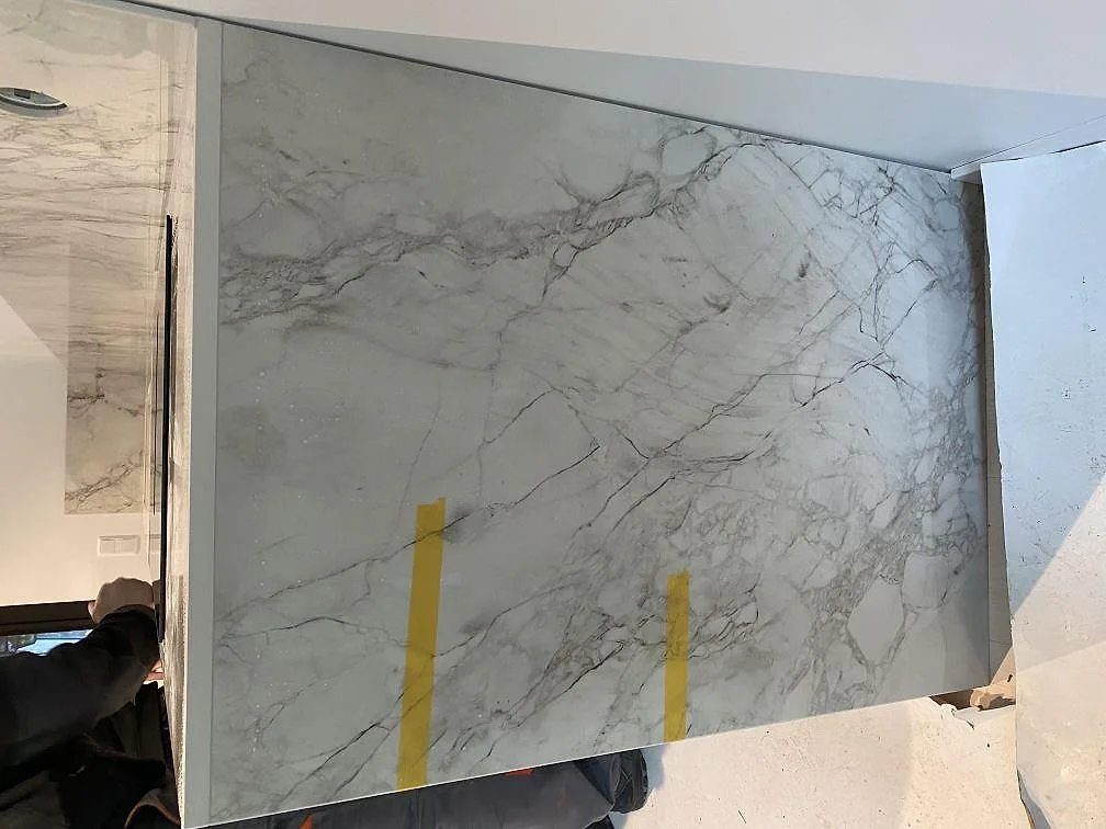 Sidostycke och stänkskydd i polerad Dekton Bergen med tydlig grå ådring under montering i Hjärup.