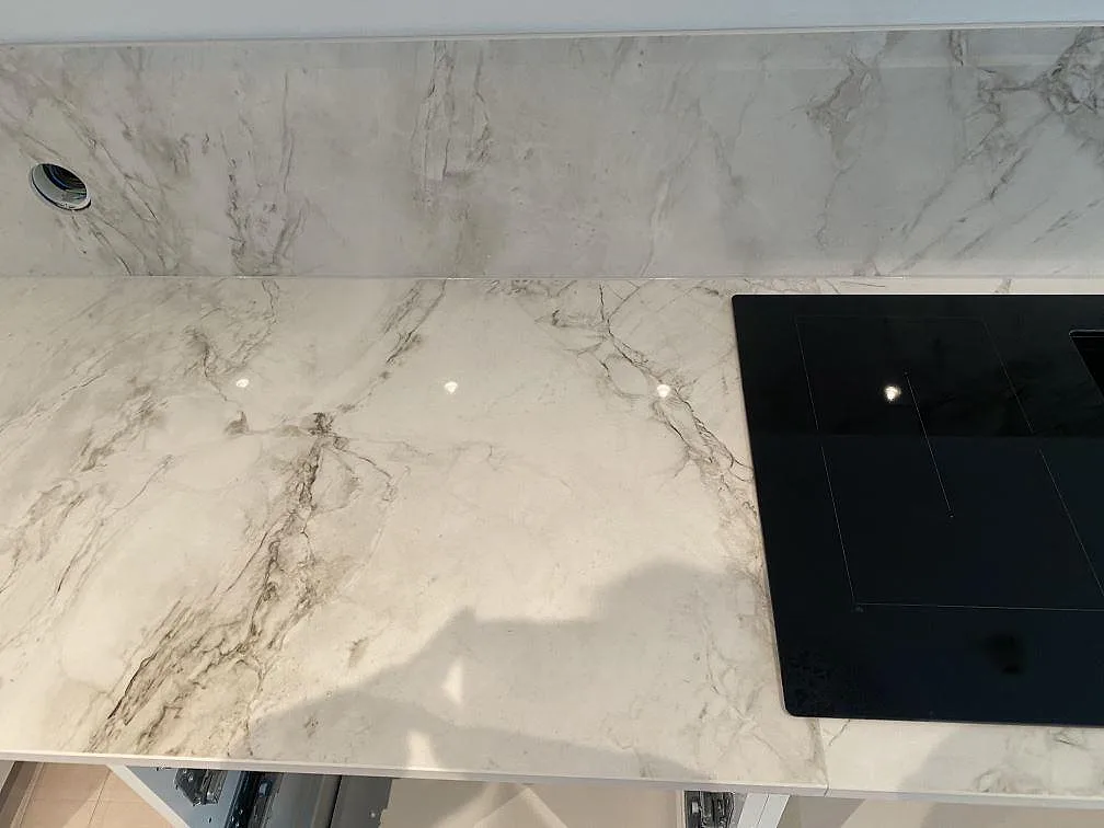 Köksbänkskiva i Dekton Bergen sedd ovanifrån med induktionshäll och tydlig grå ådring i polerad keramik, kök i Hjärup.