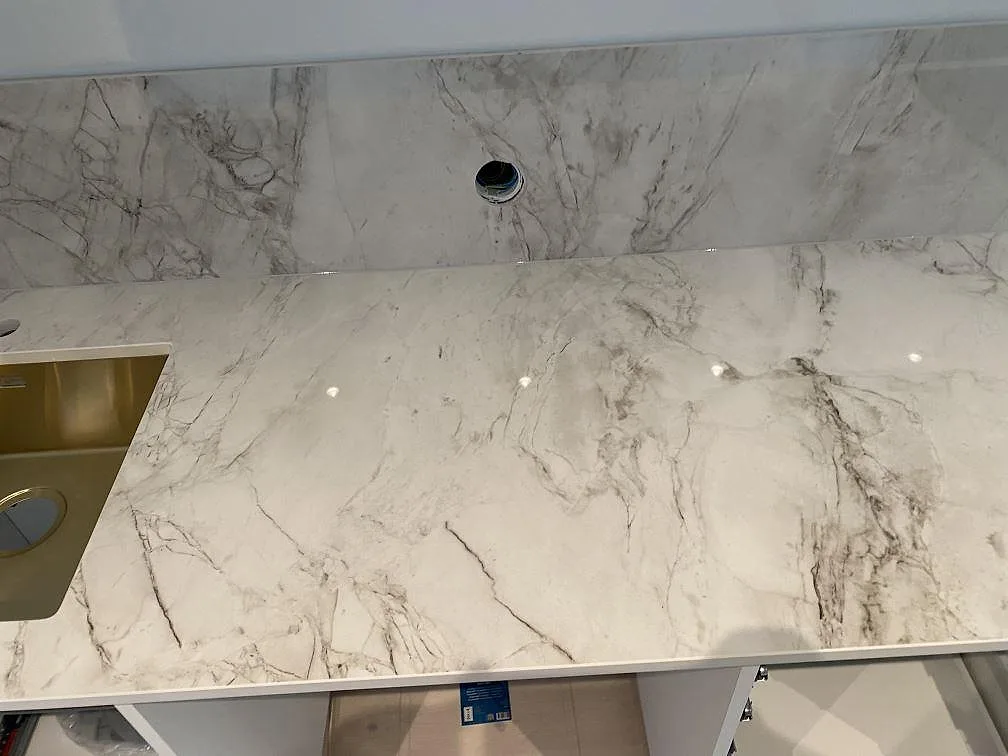 Köksbänkskiva i Dekton Bergen ovanifrån med underlimmad mässingston diskho och blandarhål, polerad keramik i ett kök i Hjärup.