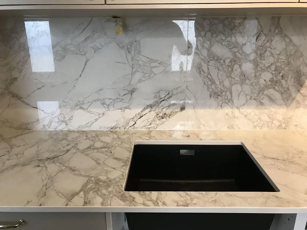 Närbild av polerad Dekton Bergen som köksbänkskiva med mörk diskho och stänkvägg i Malmö.
