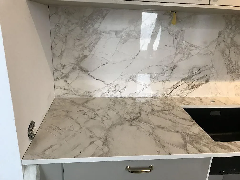 Vänster del av köksbänkskiva i polerad Dekton Bergen med grå ådring och stänkvägg i Malmö.