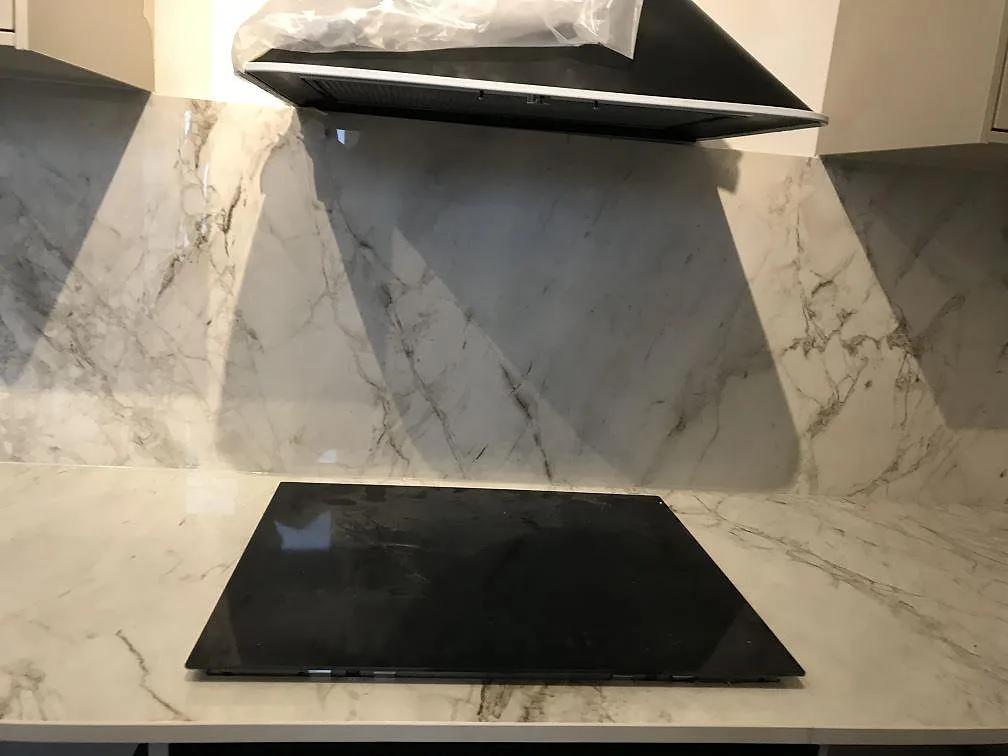 Detalj av hällzonen i polerad Dekton Bergen med matchande stänkvägg under fläkt i Malmö.