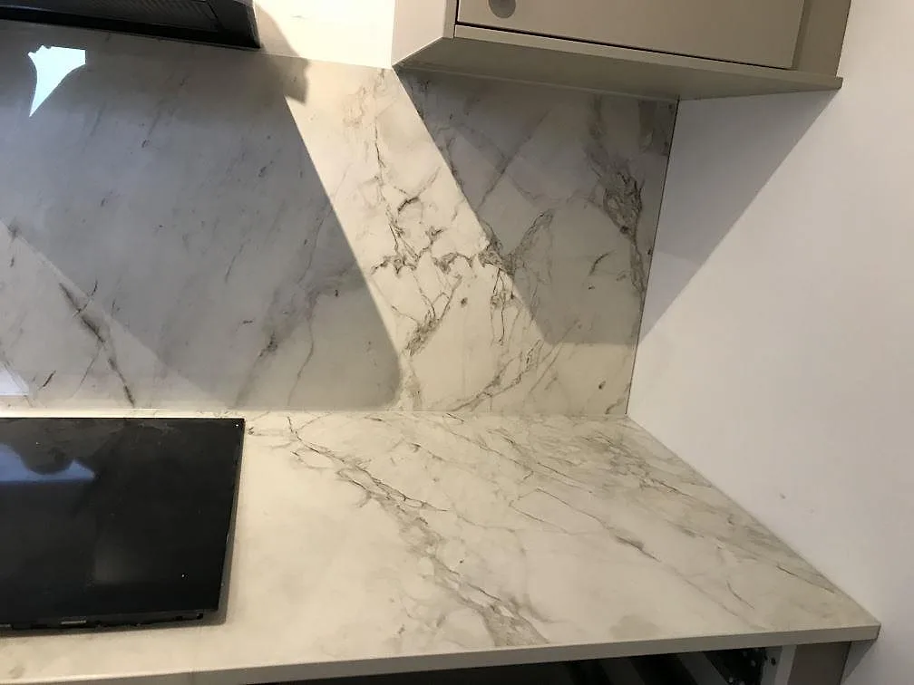 Höger del av köksbänkskiva i polerad Dekton Bergen med häll och stänkvägg i Malmö.