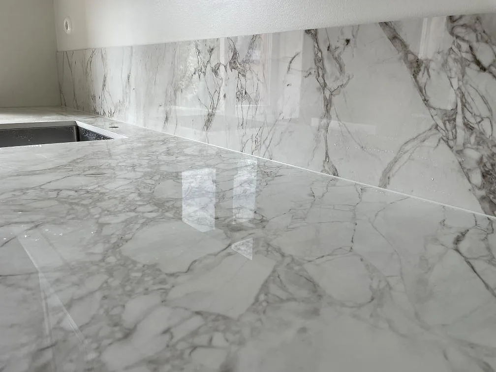 Närbild på polerad Dekton Bergen keramik med grå ådring och matchande stänkskydd i ett kök i Stockholm.