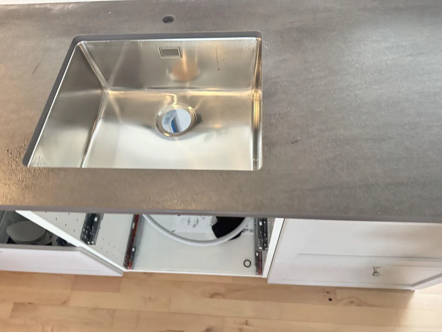Närbild på underlimmad rostfri diskho i matt Dekton Bromo med tydlig mörkgrå keramikyta i 3500 Værløse.