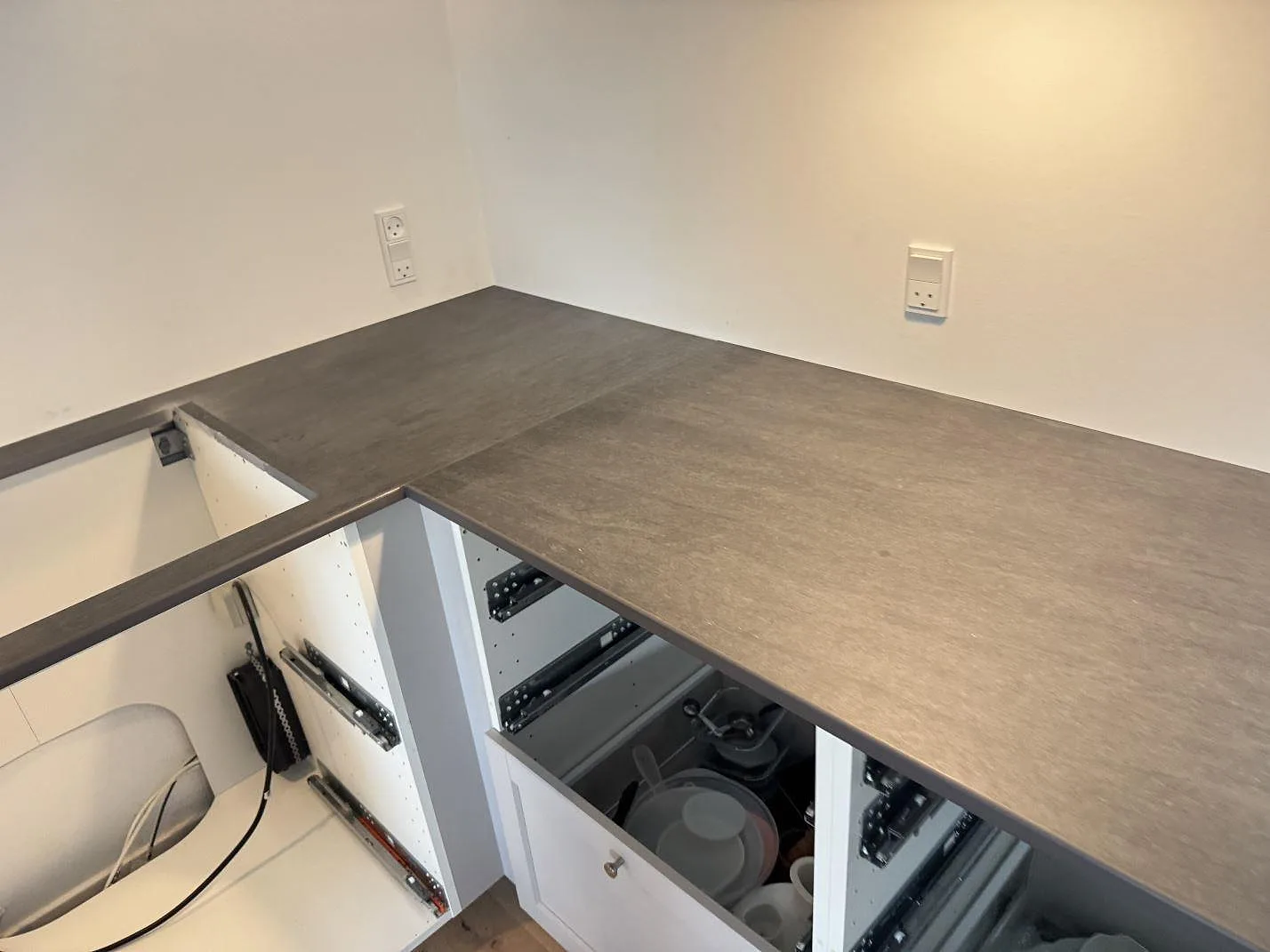 L-formad köksbänkskiva i matt Dekton Bromo med urtag för häll och öppna stommar i 3500 Værløse.