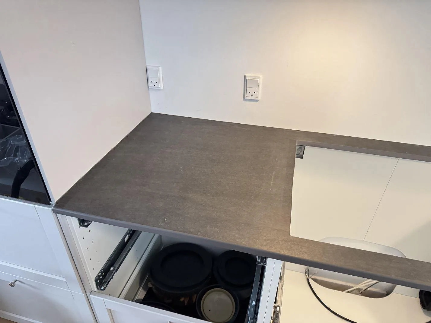 Köksbänkskiva i matt Dekton Bromo vid hörn med hällurtag och vit köksinredning i 3500 Værløse.