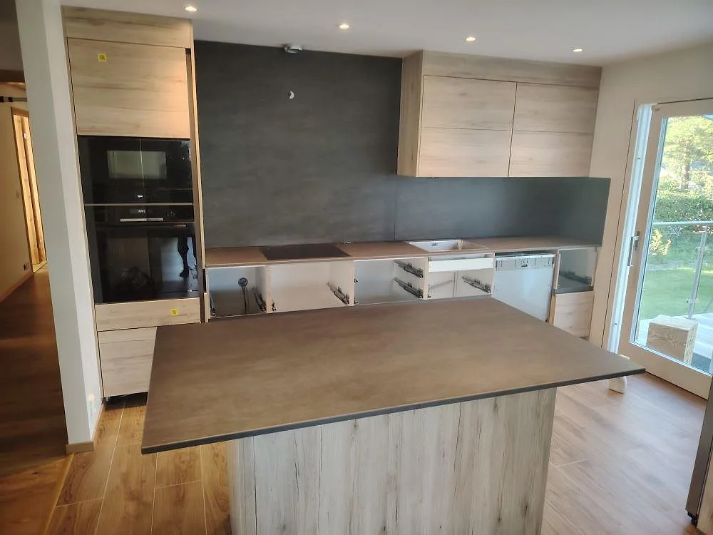 Köksbänkskiva och köksö i matt Dekton Bromo, keramik, med 8 mm stänkskydd och synlig häll i ett kök under montering i Järfälla.
