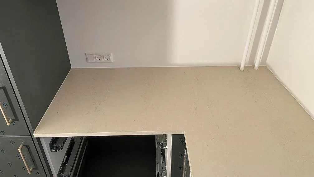 Hörnsektion av matt Dekton Danae bänkskiva monterad mot vägg och högskåp i ett kök i Gentofte.