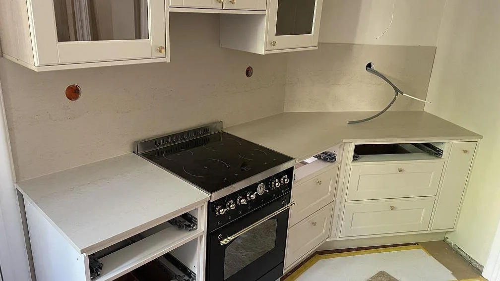 Köksbänkskiva i matt Dekton Danae runt en fristående spis, med stänkskydd i samma keramik i ett kök i Göteborg.