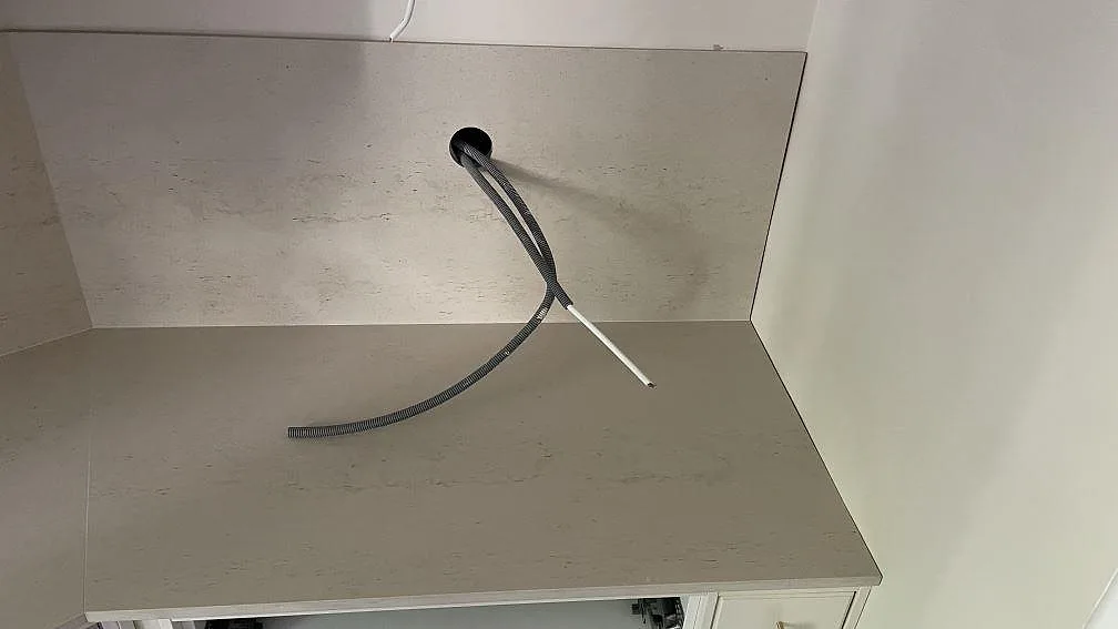 Detalj av sidobänk i matt Dekton Danae med stänkskydd och eldragning under montering i ett kök i Göteborg.