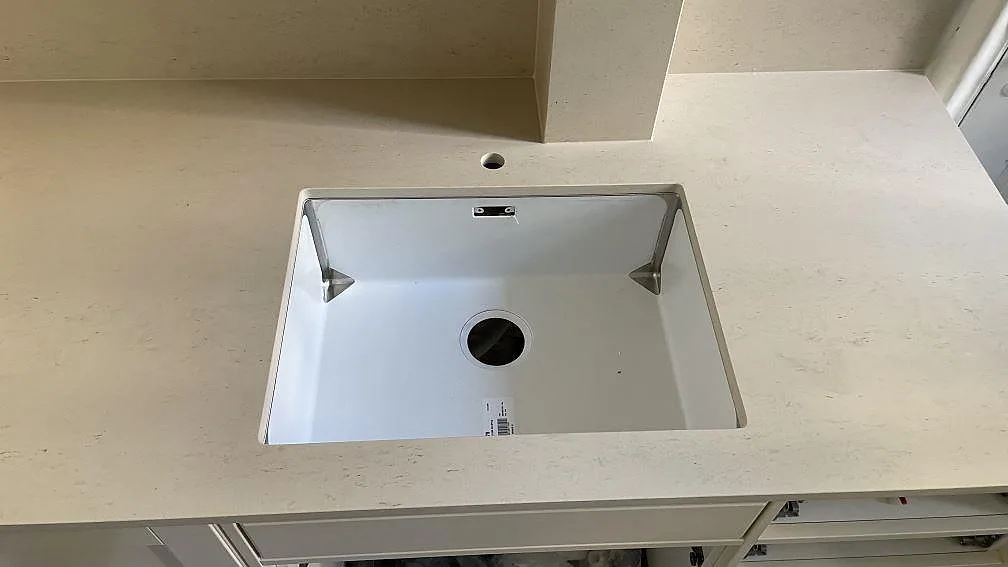 Närbild på diskhon och kranhålet i en matt köksbänkskiva av Dekton Danae med ljus stenådring i Göteborg.