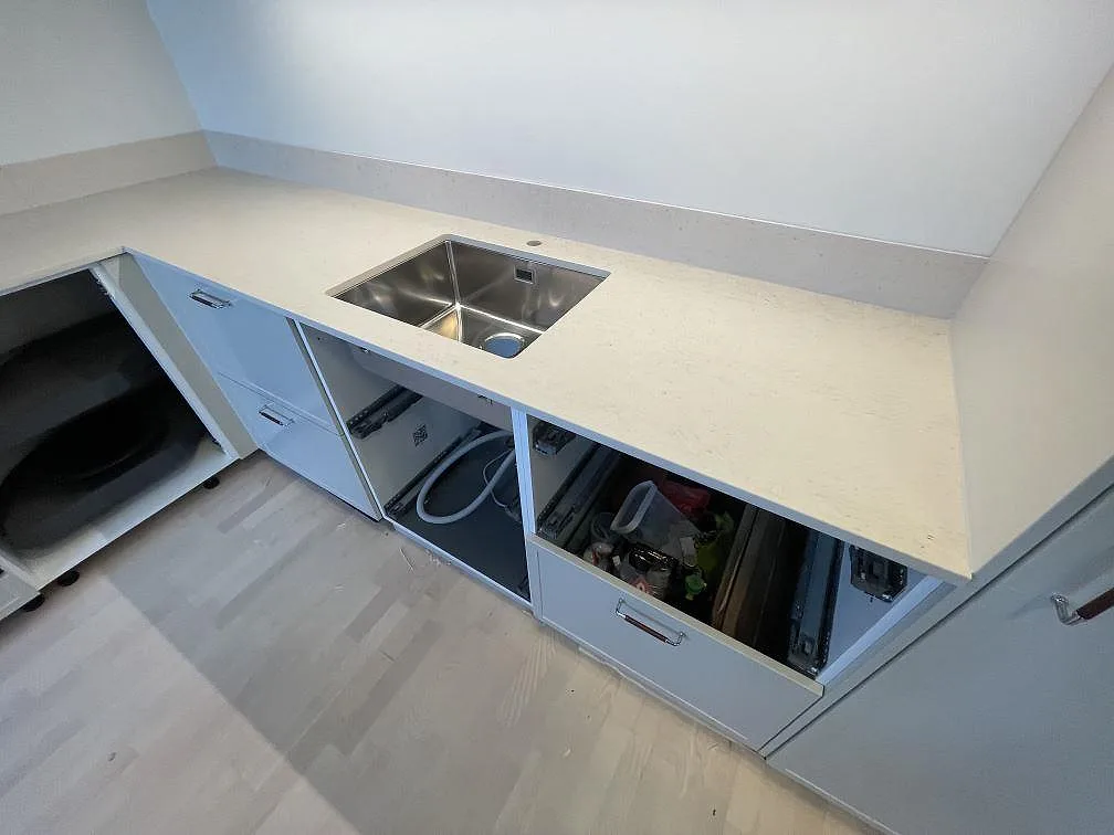 Närbild på underlimmad rostfri diskho i en bänkskiva av matt Dekton Danae keramik med låg stänkkant i Hägersten.