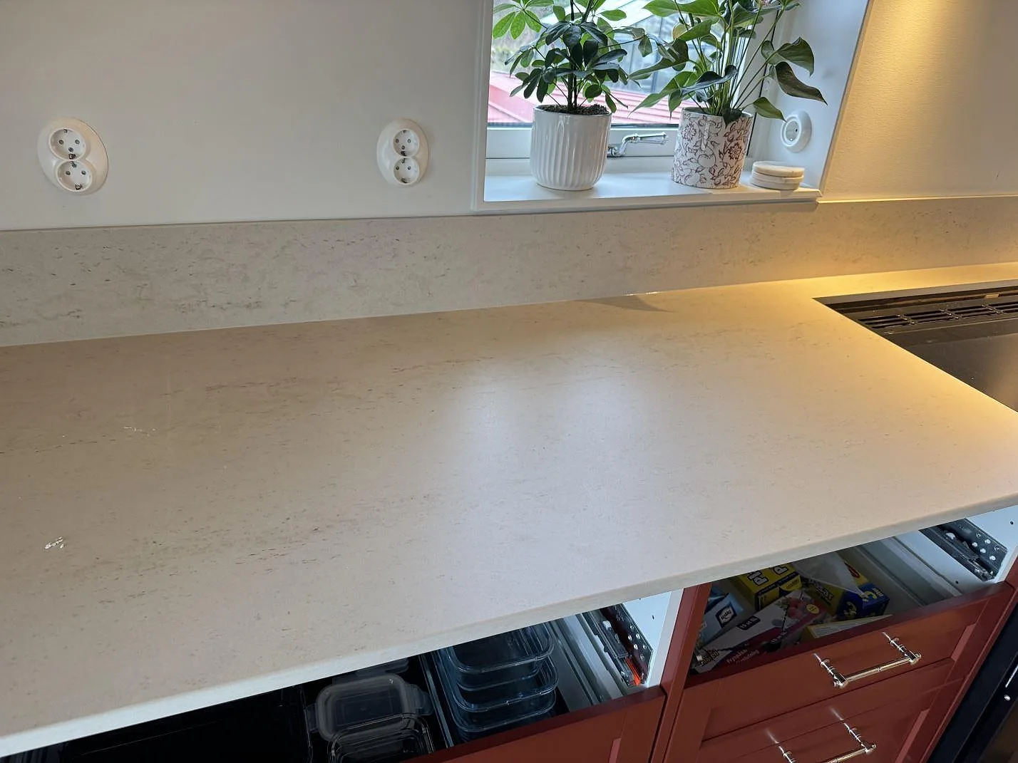 Matt köksbänkskiva i Dekton Danae keramik med låg stänkkant, fönster och hällzon i köket i Hakenäset.