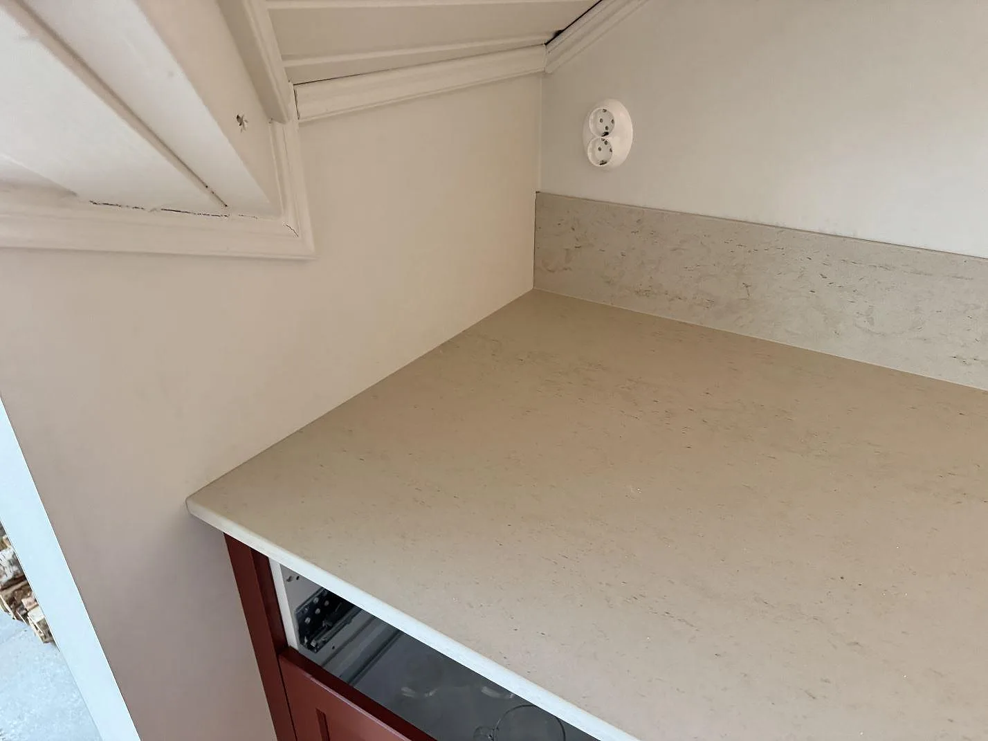 Hörn av köksbänkskiva i matt Dekton Danae keramik med stänkskydd under vägguttag i Hakenäset.