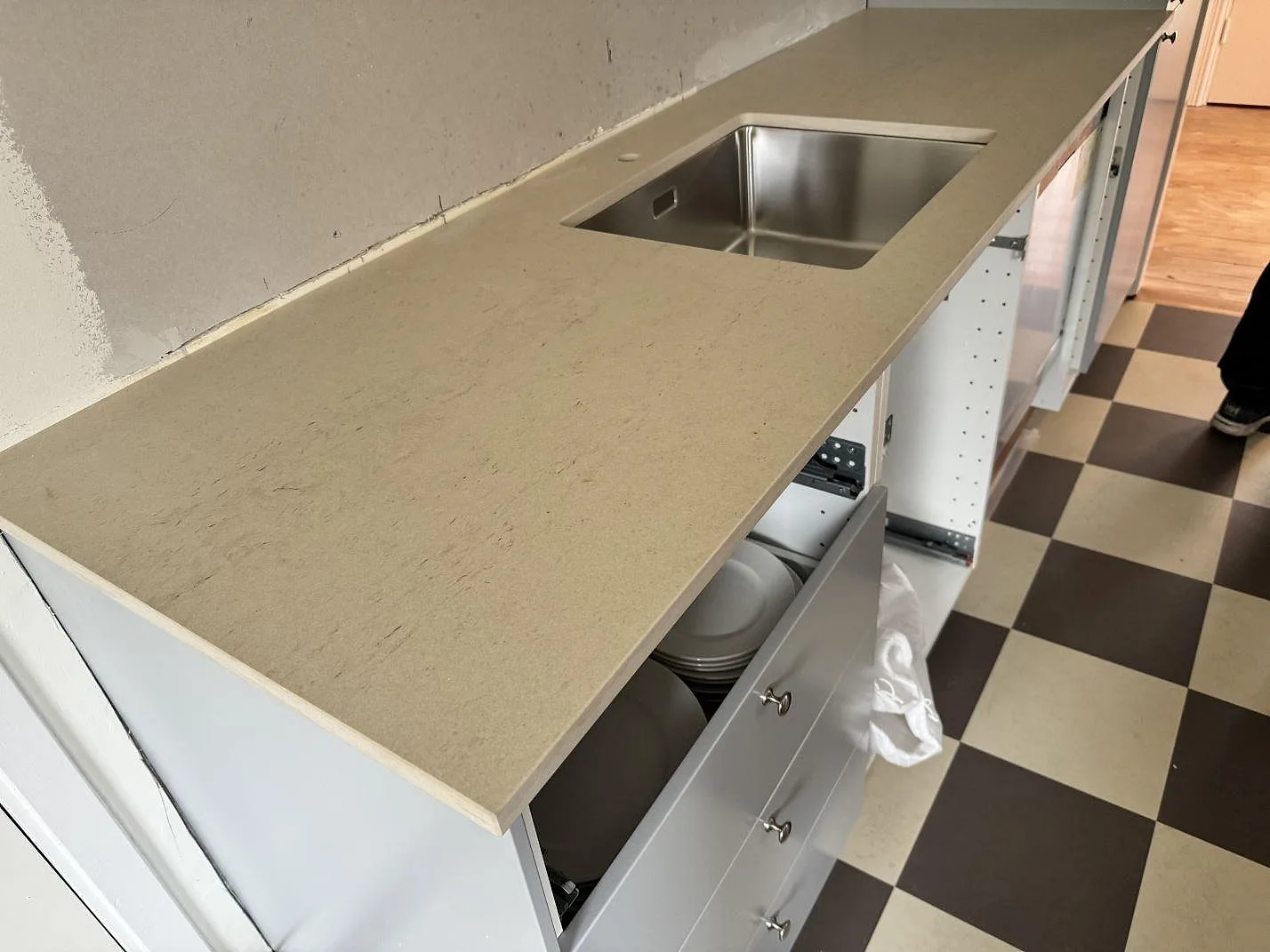 Matt köksbänkskiva i Dekton Danae med underlimmad rostfri diskho och rutigt köksgolv i Höör.