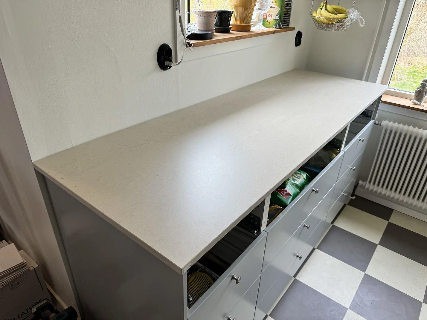 Köksbänkskiva i matt Dekton Danae, 20 mm, på ljusa skåp med rutigt golv i ett kök i Höör.