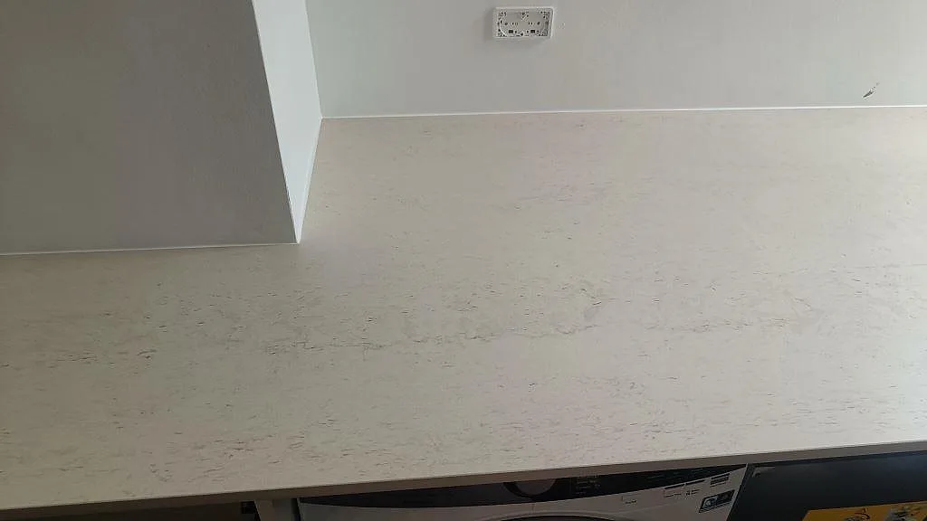 Ljus matt Dekton Danae keramik som köksbänkskiva med varm ådring och tvättmaskin under bänken i København N.