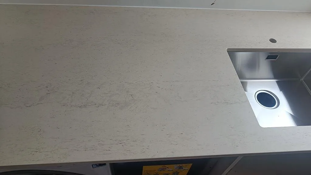 Matt Dekton Danae köksbänkskiva i ljus keramik med rostfri diskho och separat blandarhål i ett kök i København N.