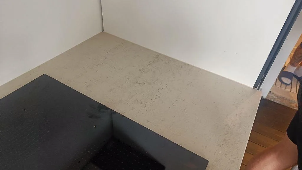 Matt Dekton Danae köksbänkskiva i ljus keramik runt en svart induktionshäll, sedd uppifrån i ett kök i København N.
