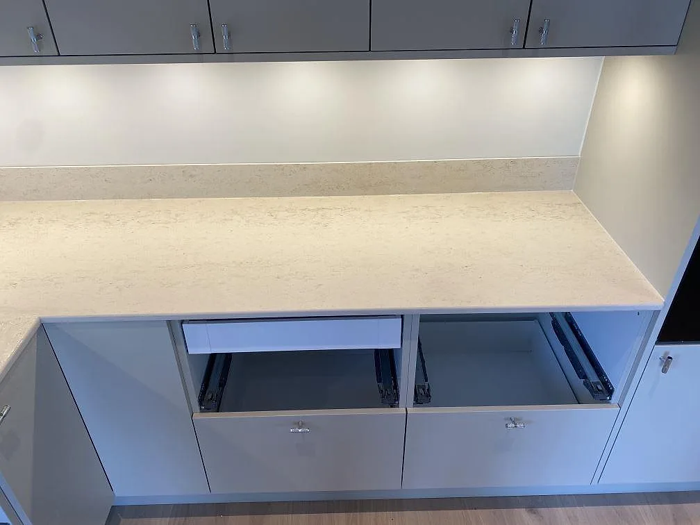 Rak bänkrad i matt Dekton Danae keramik med låg stänkkant och öppna köksstommar under montering i Lerum.