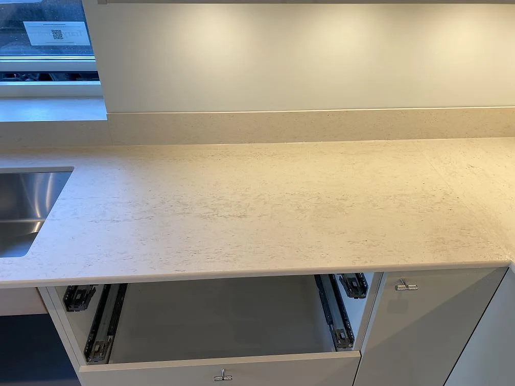 Lång arbetsyta i matt Dekton Danae keramik med låg stänkkant och öppna lådstommar i ett kök i Lerum.